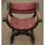 A 19th century oak x-framed elbow chair with damask upholstery seat and back, raised on lion paw