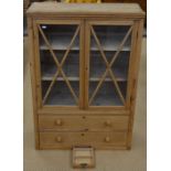 A small pine display cabinet with glazed doors enclosing two shelves and two long drawers over a