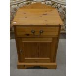 A small pine bedside cabinet with a single drawer and panelled cupboard door