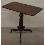 A rectangular mahogany tilt-top side table with a turned column and triform supports with castors