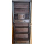 A narrow stained pine open bookcase with a small panelled cupboard and single drawer