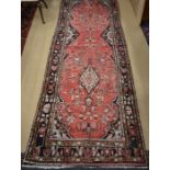 A Persian Hamadan dark ground runner with a stylised floral design, red border, 290 x 105 cm