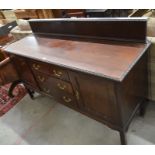 An Edwardian mahogany sideboard with panelled cupboards flanking three central drawers, raised on