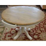 A modern circular pine dining table on painted base with two frieze drawers and quad support