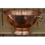 A large copper punch bowl on stepped foot with twin ring handles