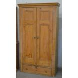 A tall waxed pine hall cupboard with panelled doors enclosing four shelves over a single drawer