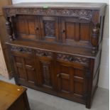 A 17th century style caved oak court cupboard with panelled doors and three drawers