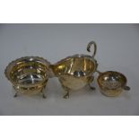 An Edwardian silver cream jug, sugar bowl and tea strainer