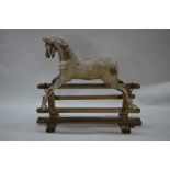 A carved wood rocking horse on frame