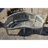 A teak weathered garden bench of kidney form