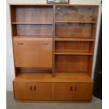 A mid century G-plan teak wall unit fitted with fall front drinks cupboard, sliding glass doors