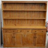 A large stained pine dresser, the plate rack with two open shelves on a base with three drawers over