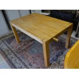 A modern light oak rectangular dining table on square supports, 140 x 90 cm