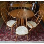 An Ercol extending circular elm breakfast table c/w leaf, 114 cm diam (closed) to/w six swan back