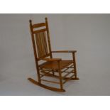 A wooden spindle back rocking chair with turned supports and slatted seat