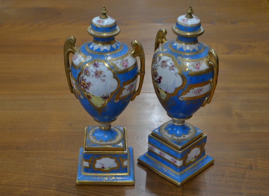 A pair of Continental blue-ground urn vases and covers in the Sevres manner, with floral-painted and