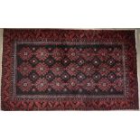 A Balouch dark ground rug with repeating stylised design within repeating border, 180 x 105 cm
