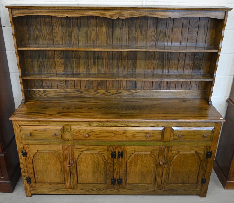 An elm dresser, the wide plate rack with two shelves on a base with three drawers over panelled