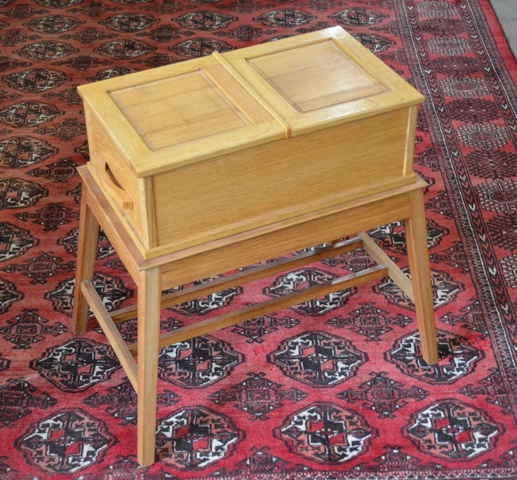 A small light oak sewing/work table with hinged top and side drawer raised on splayed supports