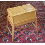 A small light oak sewing/work table with hinged top and side drawer raised on splayed supports