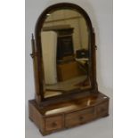 A mahogany framed arched and bevelled toilet mirror on three drawer bow front platform base