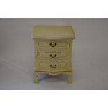 A French cream painted bedside chest with three serpentine front drawers, carved supports with