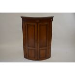 A 19th century oak mahogany and inlaid barrel front hanging corner cupboard with a pair of