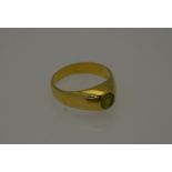 A yellow metal ring set with single circular peridot