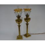 A companion/matched pair of brass column oil lamps