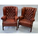A pair of Georgian style brass studded buttoned brown-red leather wing armchairs
