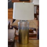 A gold and clear dimpled glass lamp base with cream fabric shade