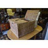 Large wicker storage trunk with twin-hinged top and leather strap