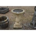 A composite cast bird bath on baluster form column and stepped square base