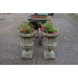 A pair of Georgian style weathered cast stone urn planters