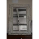 A large rectangular mirror in white painted and distressed carved surround