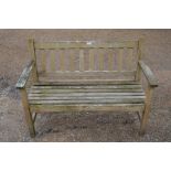 A weathered slatted teak two-seater garden bench
