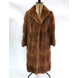 A mid brown fur coat with shawl collar and turned cuff sleeves