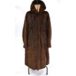 A brown fur long coat with shawl collar and raglan sleeves