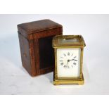 An antique brass carriage clock with white enamelled dial
