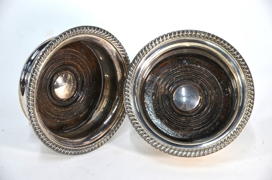 A pair of silver bottle coasters with gadrooned rims and turned wood bases