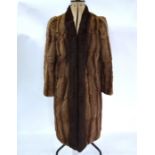 A mid brown fur coat with shawl collar and three-quarter length sleeves