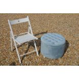 A modern circular ottoman/footstool with buttoned light blue upholstery