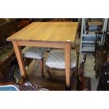 A modern light oak square dining table on tapering supports