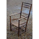 An antique oak cane seated open armchair