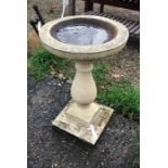 A weathered cast stone bird bath