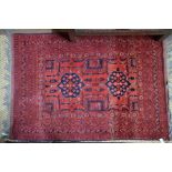 A small Afghan rug, the linked twin lozenge design on rust-red ground