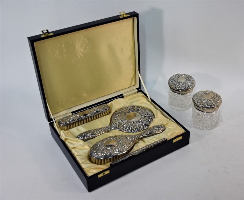 A four-piece embossed silver brush set with hand mirror, in fitted presentation case