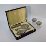 A four-piece embossed silver brush set with hand mirror, in fitted presentation case