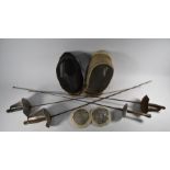 Two vintage fencing masks, a pair of breast-guards and foil and three sabres