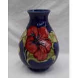 A Moorcroft pottery baluster vase decorated with pink and variegated hibiscus flowers to a blue